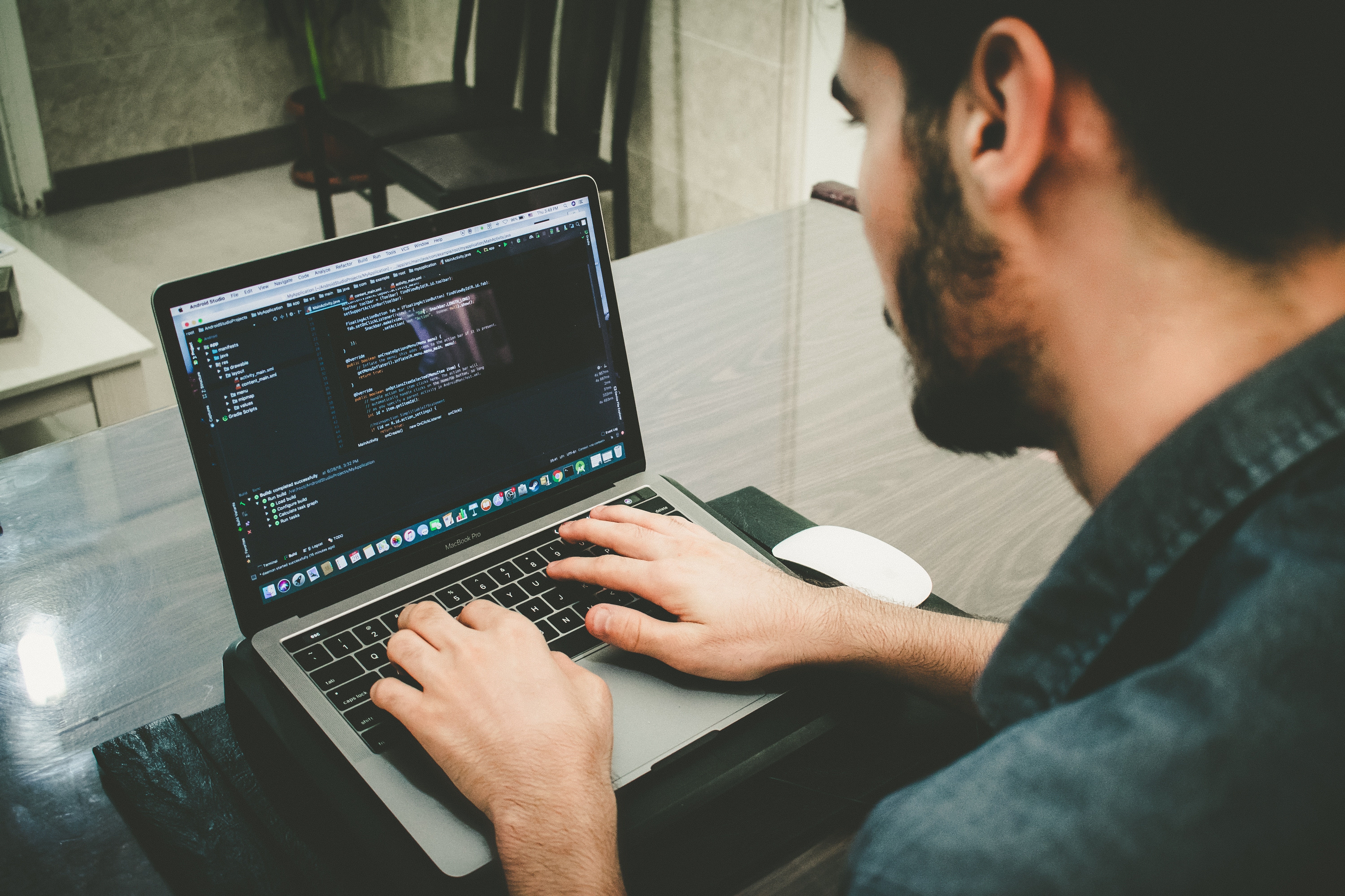 A young man working on his laptop, writing code to design a website.