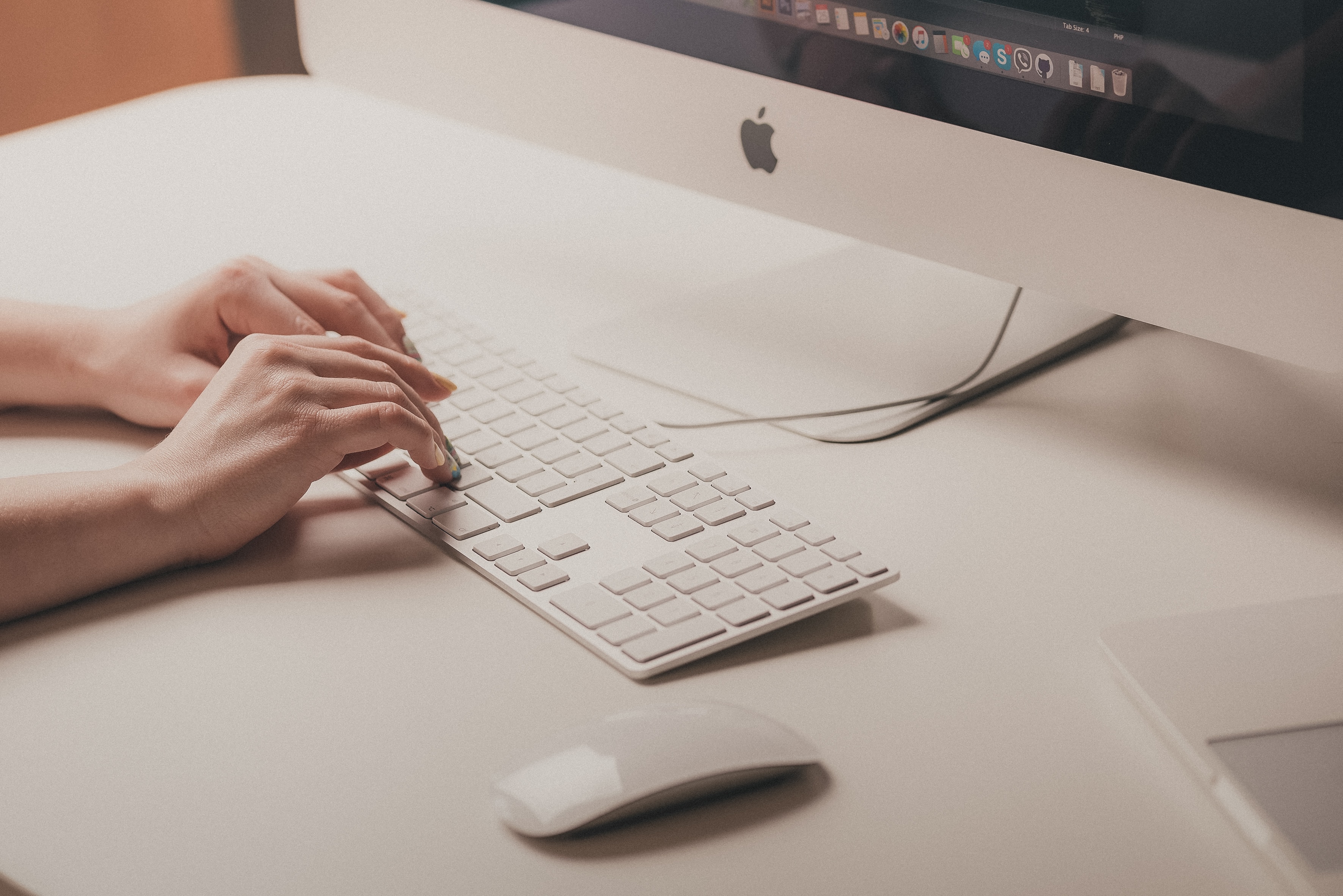 A close-up image of a person typing on a Mac computer.